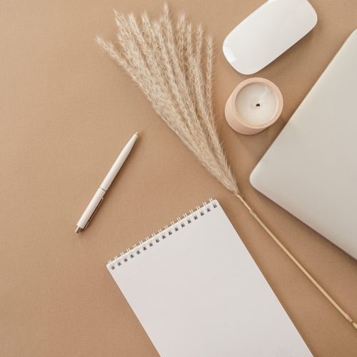 Flatlay Of Spiral Flip Notebook With Blank Paper Sheet. Laptop, Pampas Grass, Stationery On Beige Peachy Pastel Background Table. Minimalist Home Office Desk Workspace. Top View Mockup Copy Space.